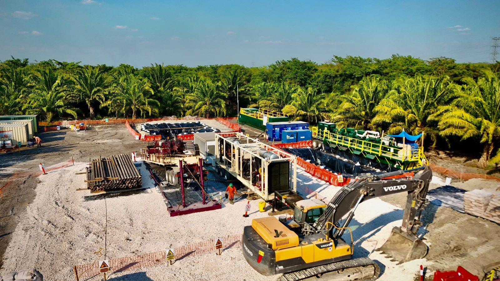 Sitio de perforación con planta de lodos y excavadora Volvo